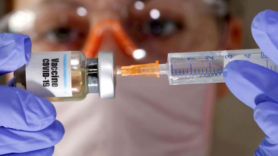 FILE PHOTO: A woman holds a small bottle labeled with a "Vaccine COVID-19" sticker and a medical syringe in this illustration taken April 10, 2020. REUTERS/Dado Ruvic//File Photo